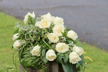 Flower arrangement. White funeral flowers on a gravestone in a cemetery. Relatives have brought...