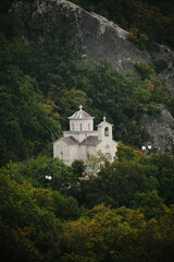 Fototapeta premium A small old stone Christian church on a serpentine in the mountains on the way to the most famous and popular place among tourists - Ostrog Monastery. Montenegro country.