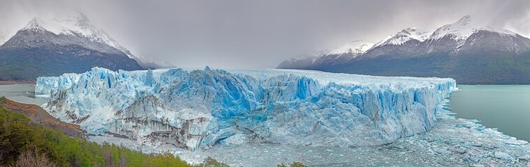 Perito Moreno Glacier with its dramatic icy wall and surrounding snowy mountains in Patagonia