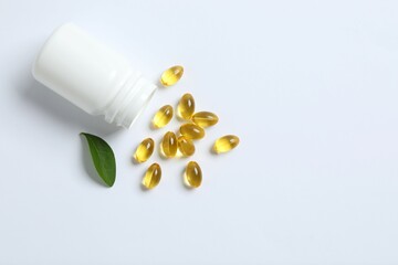 Capsule of omega 3, 6, 9 fish oil, vitamin, food supplement pouring out of medicine bottle on white background 