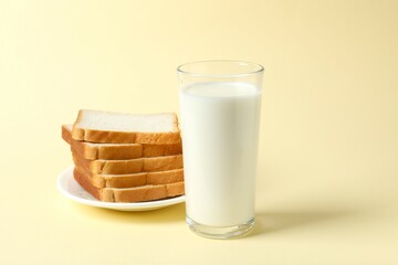 Glass of milk with bread on color background