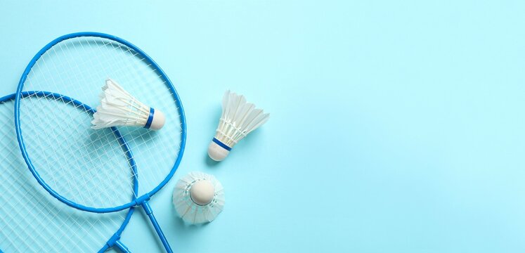 Badminton rackets and white badminton shuttlecocks on color background 