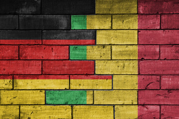 colourful painted big flag of germany and flag of mali on a massive old brick wall background....