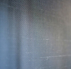 Close-Up Detail of a Metallic Wire Mesh with Textured Background