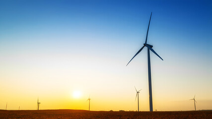 Obraz premium A wind farm on a sunny day with turbines spinning.
