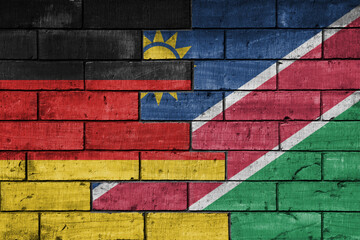 colourful painted big flag of germany and flag of namibia on a massive old brick wall background....