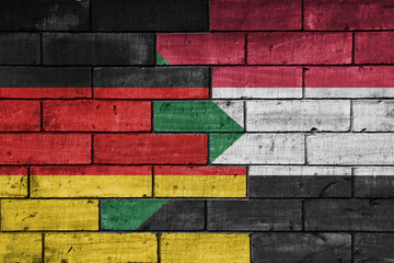 colourful painted big flag of germany and flag of sudan on a massive old brick wall background....