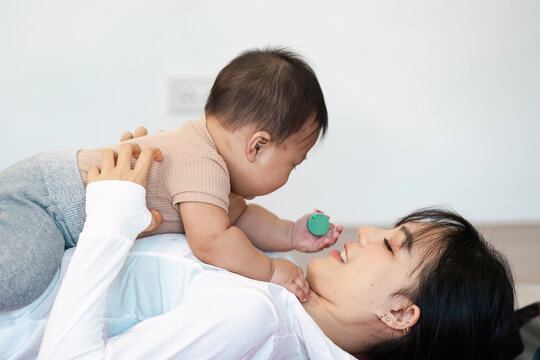 Multitasking mother engaging with her joyful baby during playtime at home - Powered by Adobe