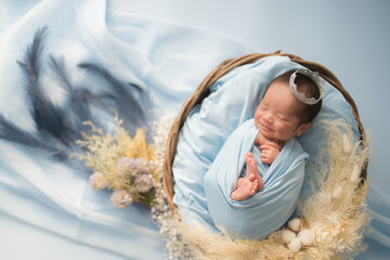 ニューボーンフォト_おくるみに包まれて幸せそうに新生児微笑を見せてすやすや眠る生まれたての赤ちゃん