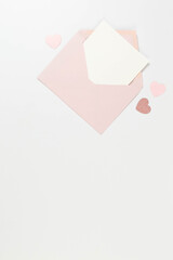 Top view of pink envelope, white card on white background. Valentine's day, pink hearts, pink glitter heart, love. Post flat lay, copy space.