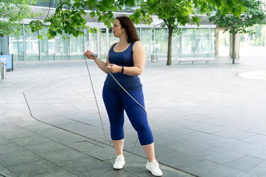 woman and sports, exercise for weight loss in the fresh air. Happy curvy woman doing workout routine outdoor at city park