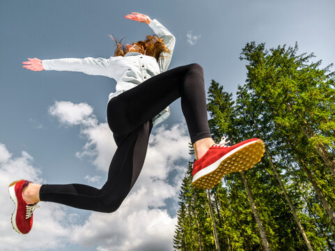 Low angle female athlete jumping against scenic view of blue sky