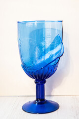 Broken blue glass on a white wooden background. Two pieces.