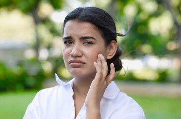 Unhappy, sad, negative feeling South Asian woman having problem with face skin care, acne, dry...