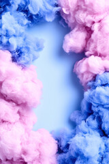 Fototapeta premium A vibrant mix of pink and blue smoke clouds encircles a soft blue background, creating a dreamy and whimsical atmosphere.