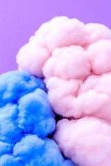 Fototapeta premium Cotton candy clouds in pastel blue and pink hues create a whimsical and dreamy atmosphere against a vibrant purple background.