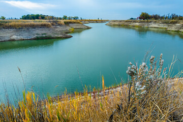 Reservoir with calm water and dry grass on the shore