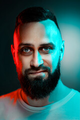 Studio portrait with colorful light of young handsome bearded man.