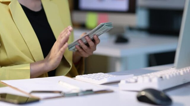 Businesswoman skillfully counting us dollar bills at her desk, her financial acumen and professionalism.
