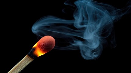 A matchstick ignites, revealing a vibrant orange flame while wisps of smoke gracefully rise into the air. The dark background emphasizes the glowing tip and smoke patterns