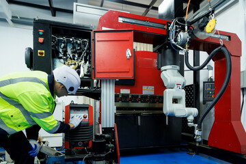 Robot engineer student learning to operating an industrial robotic welding machine in factory...
