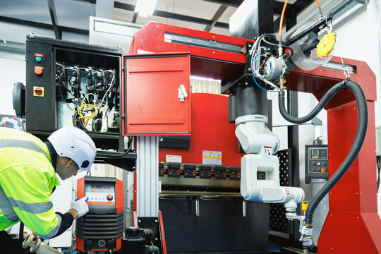 Robot engineer student learning to operating an industrial robotic welding machine in factory workshop at manufacturing. Modern manufacturing technology education and ai automation concept.