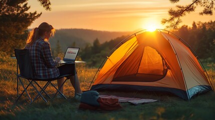 Woman works on laptop outdoor, camping tent. Sunrise, Summer holiday. Relaxed workplace in nature. Freedom, connection. Remote work, digital nomad concept. Morning light. Inspiring