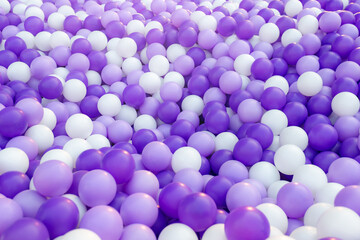 Background of purple plastic balls. Close up view of plastic balls in a ball pool at a children's indoor playground. Recreation and entertainment concept. Copy space.