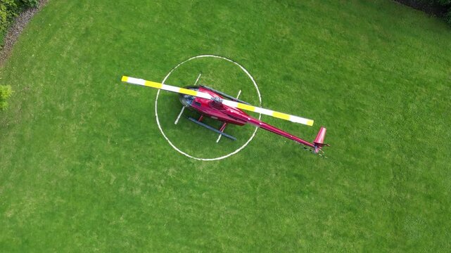 helicopter parked grass heliport vibrant red rotor blade unique perspective operational aspects circling downward aerial shot h pad drone aviation london scenic view travel air 