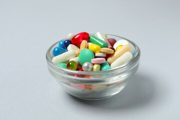 Various pills in a bowl on gray background