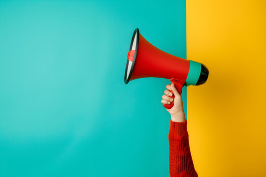 Hand holding red loudspeaker or megaphone on blue and yellow background. Banner template for promotions, sales, dissemination of information, rallies and protests with space for text