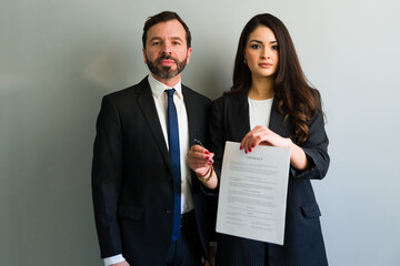 Businesspeople holding contract and pen, ready for signature