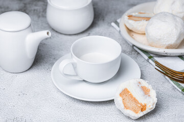 Coconut cakes on a plate and a cup of milk on a wooden background