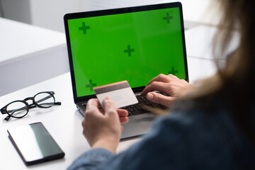 A person is actively engaged in the process of online shopping using a credit card while sitting at a laptop, taking advantage of the convenience and efficiency offered by modern technology