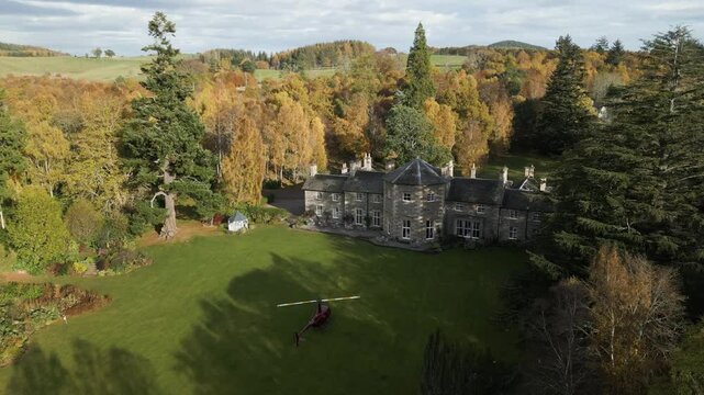 helicopter parked grass luxurious country house estate engines running preparation for departure vibrant autumn trees forest aerial view hotel mansion scenic views luxury rich 