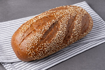 Freshly baked sesame bread resting on a striped cloth showcasing its golden crust and inviting aroma