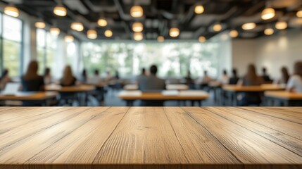 Wooden Table Top in Blurred Background of Modern Conference Room with People Seated at Desks and Natural Light Streaming In