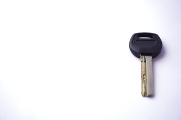 A single car key with a black plastic head and metal blade, placed on a white background, symbolizing security and transportation. 