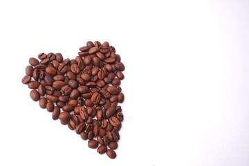 A collection of roasted coffee beans carefully arranged in the shape of a heart on a clean white background, symbolizing love for coffee and the warmth associated with enjoying a cup.