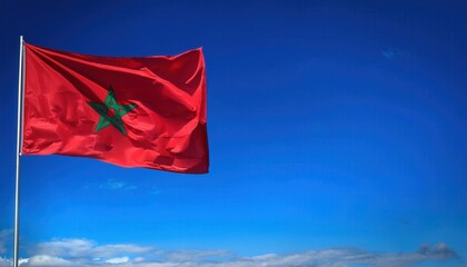 A vibrant red flag of Morocco flutters proudly on a pole, set against a clear blue sky. This display embodies the country's spirit, traditions, and sense of community