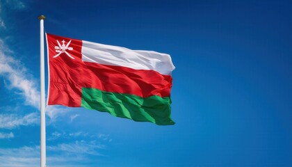 The vibrant flag of Oman flutters gracefully on a pole, set against a backdrop of a clear blue sky, embodying the spirit of nationality and cultural heritage with every breeze