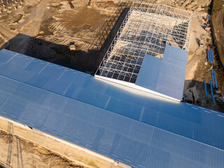 A construction site with a partially built warehouse featuring a steel framework and metal roof....