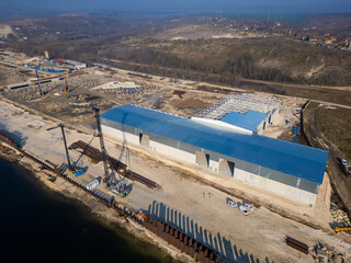 A construction site with a partially built warehouse featuring a steel framework and metal roof....