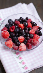 Frozen mixed fruits in a bowl - berries - strawberries, raspberries, black currants. A bowl with berries on a beautiful fabric
