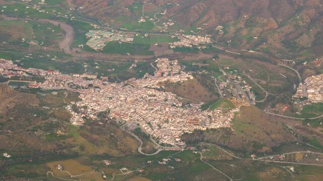 from inside airplane passenger window alora village town spain aircraft approaches airport for landing aerial view spanish approach rural landscape 