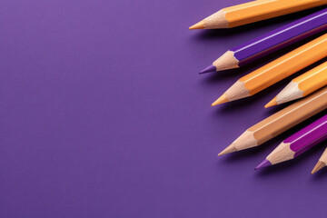 A minimalist composition featuring sharpened purple and yellow pencils arranged on a matching purple background, creating a striking monochrome aesthetic.  

