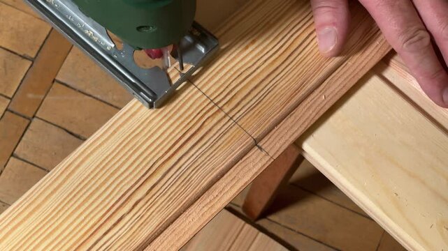 Sawing of wooden plank with jigsaw along the marking line