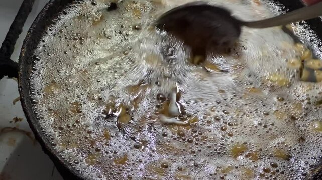 Duck fat rendering on frying pan, stirring it with spoon