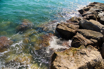 Waves gently lap against rocky shoreline on a sunny day by the water