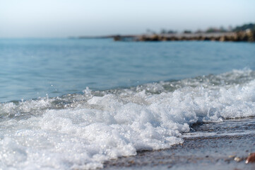 Gentle waves lap against the shore at a tranquil coastal landscape during early morning light